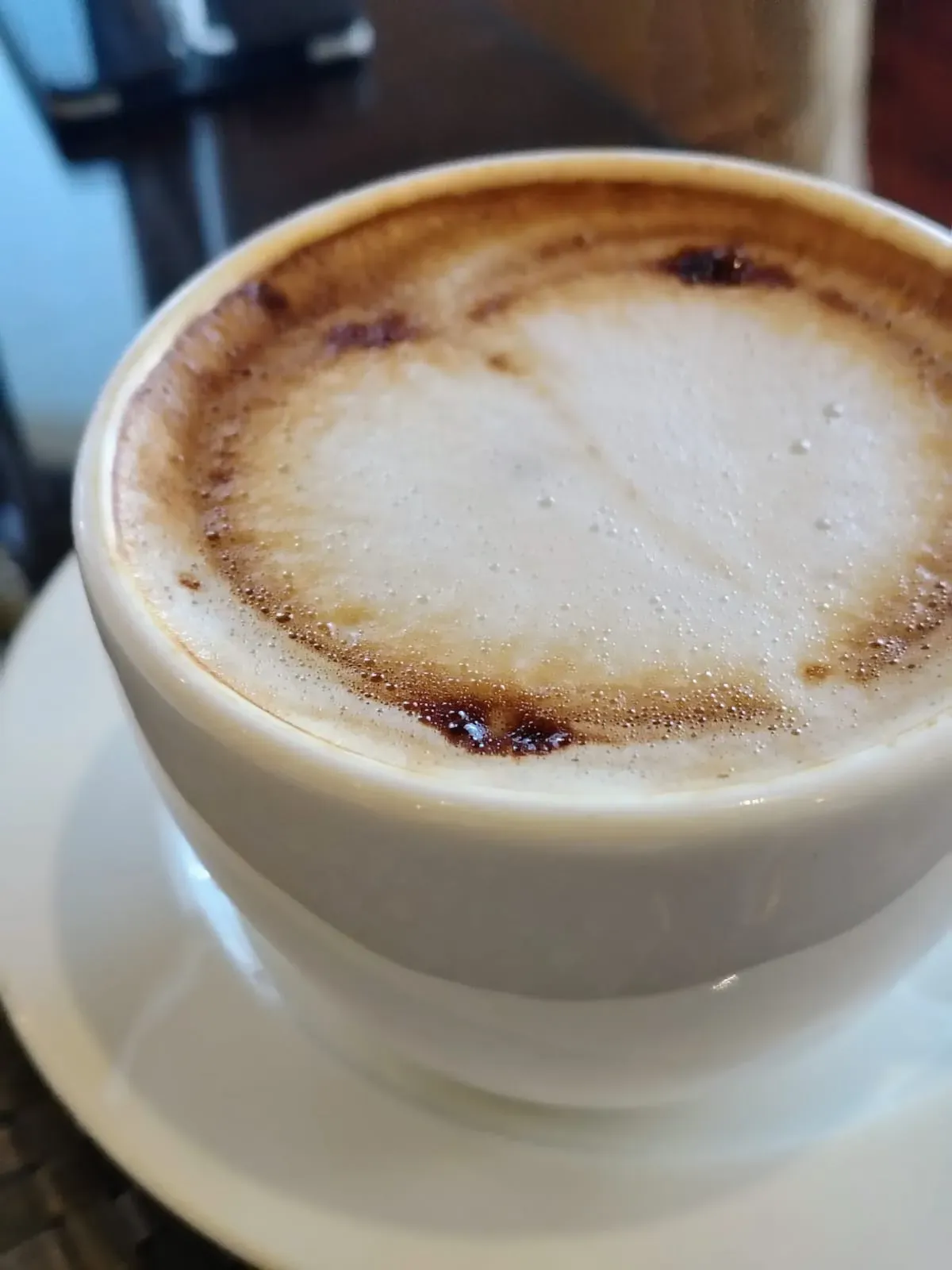 A frothy coffee in a white cup, up close